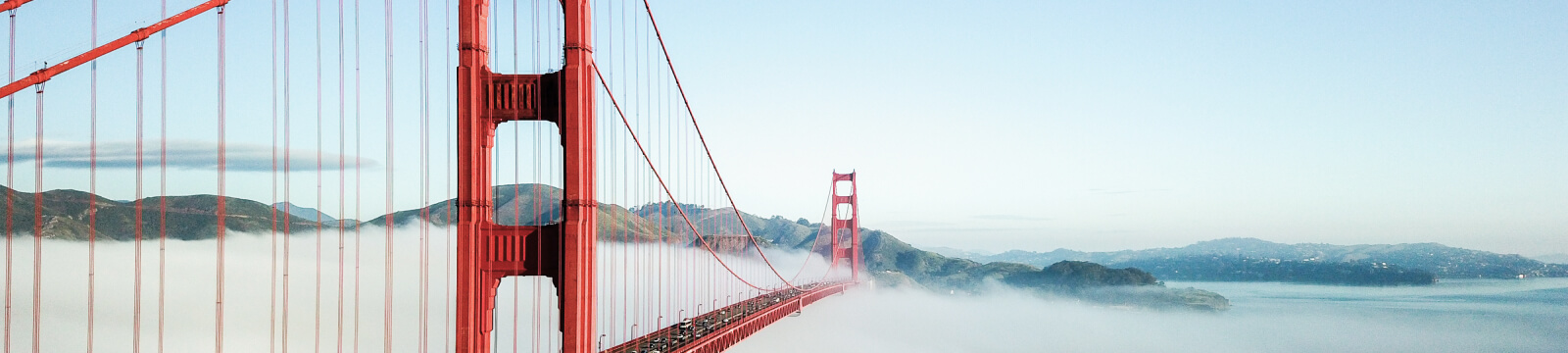 Red bridge stretching over foggy water